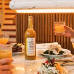 Alain Milliat ginger concentrate 75cl bottle displayed on a restaurant table with food and drinks in a lifestyle setting