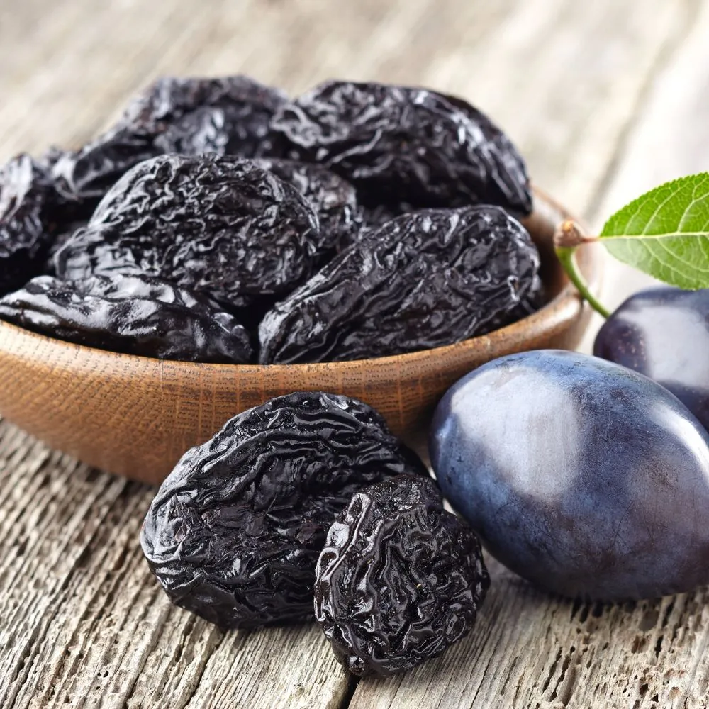 Traditional French Agen prunes with fresh plums on a rustic wooden table