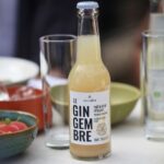 Alain Milliat sparkling ginger drink 250ml bottle displayed on a dining table with glasses and food in a lifestyle setting
