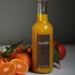 Alain Milliat PGI Corsican clementine juice 330ml bottle displayed with fresh Corsican clementines in a lifestyle setting