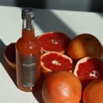 Alain Milliat pink grapefruit juice 330ml bottle displayed with fresh pink grapefruits in a lifestyle setting