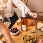 Alain Milliat sparkling Chardonnay grape juice 750ml bottle displayed on a table with food and glasses in a lifestyle setting